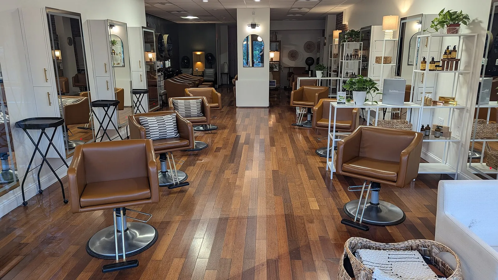 Two rows of brown leather styling chairs facing tall mirrors, on a wood floor